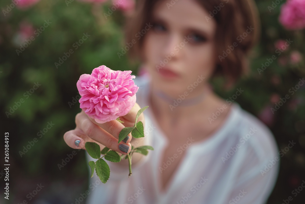 Beautiful young woman with curly hair posing near roses Beautiful young woman with curly hair posing near roses