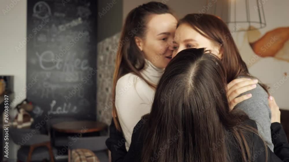 Three women friends are hugging together greeting. Friendly meeting in cafe. Friendship concept. Three women friends are hugging together greeting. Friendly meeting in cafe. Friendship concept.