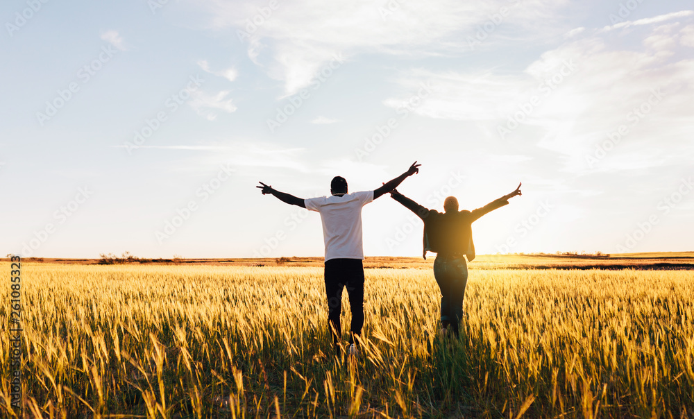 Couple walking to the sun raising hands on air Couple walking to the sun raising hands on air
