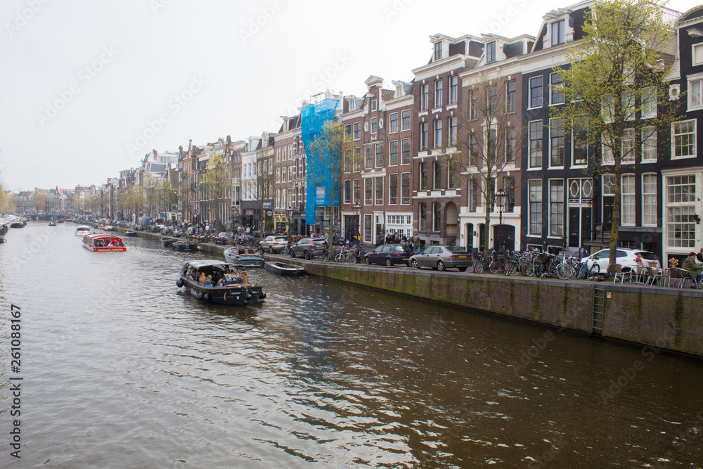 Amsterdam/Netherlands, April 06, 2019: Old streets along numerous canals in Amsterdam. River transport and bicycles