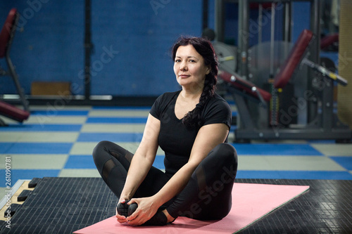 Senior woman in the gym sitting on a pink yoga mat. close-up. copy space.