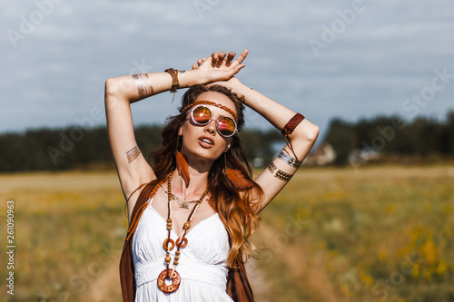 Fototapeta Pretty amazing free red-haired hippie girl dancing outdoors, feathers and braids