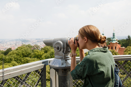 Woman looking at town view with binoculars