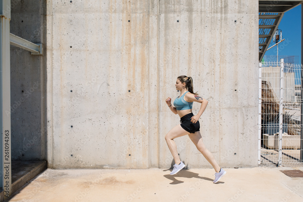 Running woman against concrete wall Running woman against concrete wall
