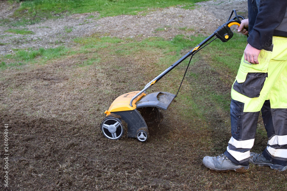 A man cuts moss in the garden with an aerator. Concept: Lawn aeration before planting lawn grass. Garden work with tools. A man cuts moss in the garden with an aerator. Concept: Lawn aeration before planting lawn grass. Garden work with tools.