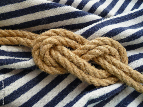 Double figure eight rope knot isolated on a striped blue white nautical shirt background. Flamand knot.