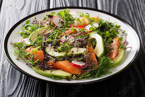 Balanced dietary salad of red fish, avocado, radish and a mix of micro green close-up on the table. horizontal