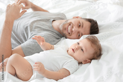 Handsome dad with his little son lying on bed at home