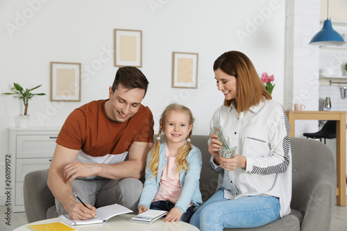Happy family counting money on sofa at home