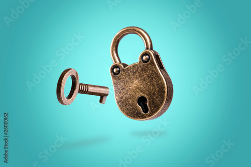 levitating closed bronze lock with key on azure background photo