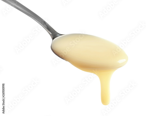 Spoon with condensed milk on white background, closeup. Dairy product photo