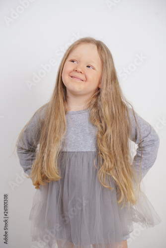 cute caucasian baby girl with long blond hair stands on white background in Studio