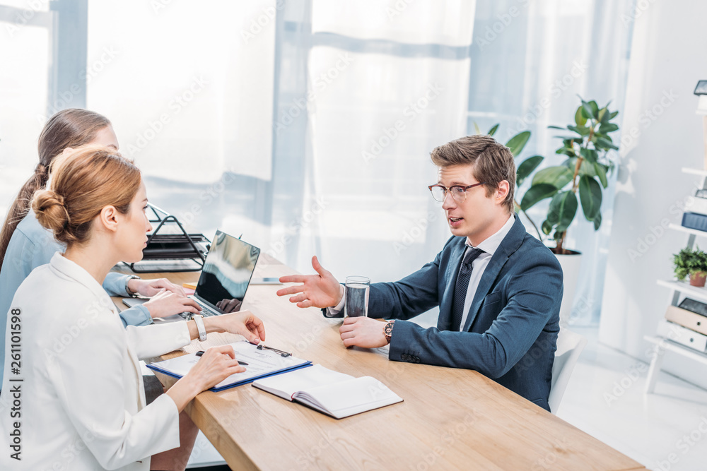 handsome employee in glasses talking and gesturing on job interview handsome employee in glasses talking and gesturing on job interview