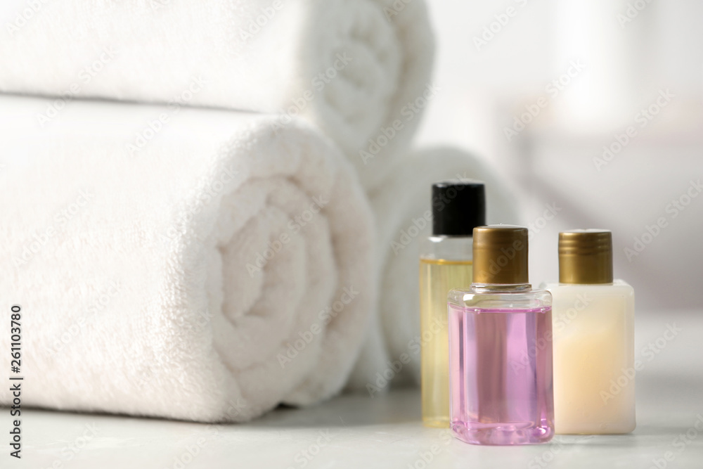 Mini bottles with cosmetic products and towels on table. Hotel amenities Mini bottles with cosmetic products and towels on table. Hotel amenities