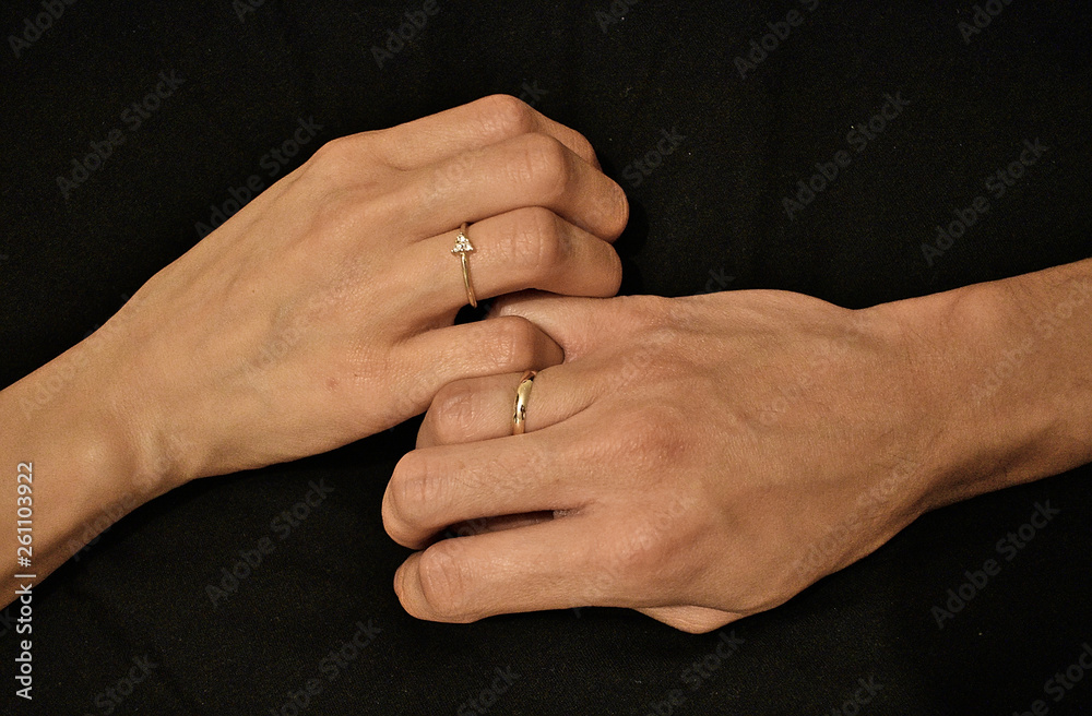 holding hands with engagement ring over a black background