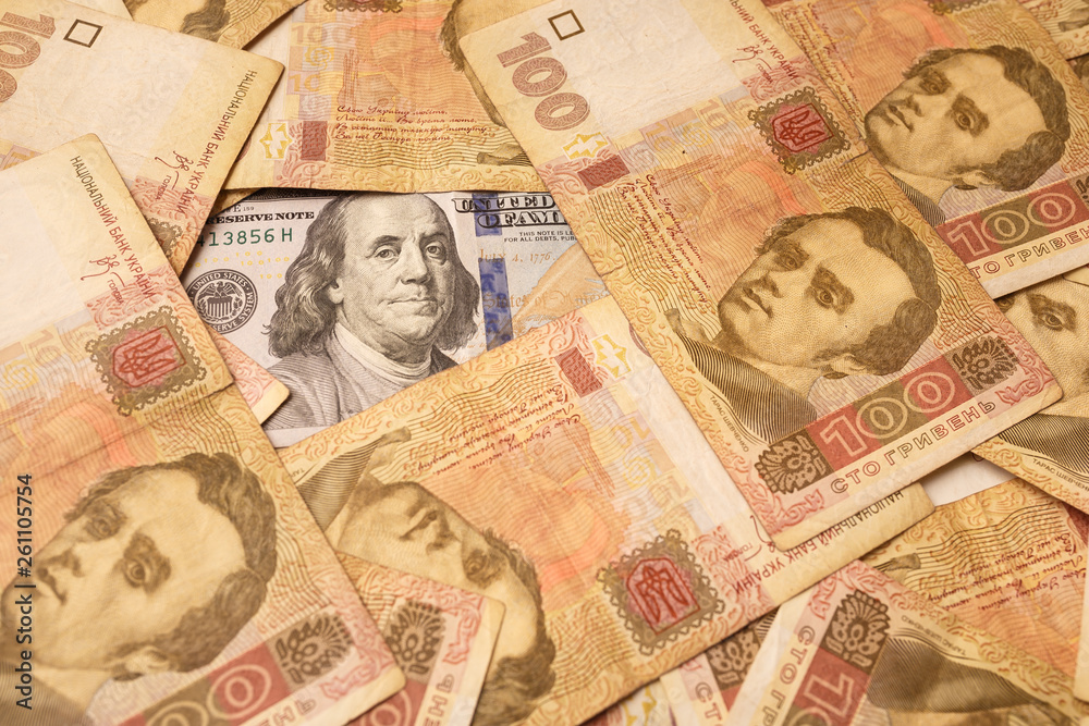 The American dollar is strewn with Ukrainian hryvnia. Portrait of Benjamin Franklin surrounded by Ukrainian banknotes. Money background The American dollar is strewn with Ukrainian hryvnia. Portrait of Benjamin Franklin surrounded by Ukrainian banknotes. Money background
