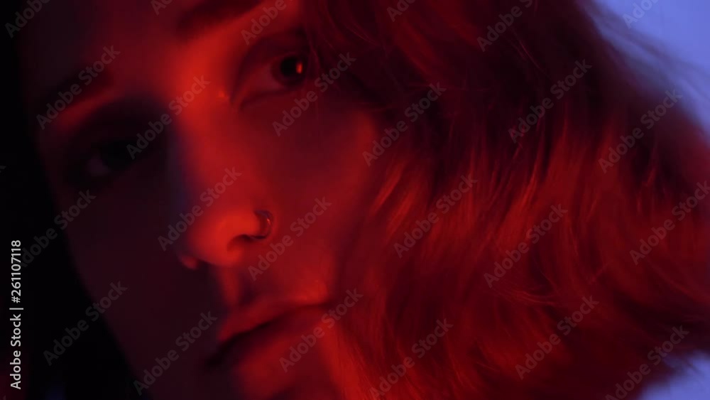 Closeup shoot of young attractive caucasian female with naked shoulder seductively looking at camera with neon blue and red background Closeup shoot of young attractive caucasian female with naked shoulder seductively looking at camera with neon blue and red background