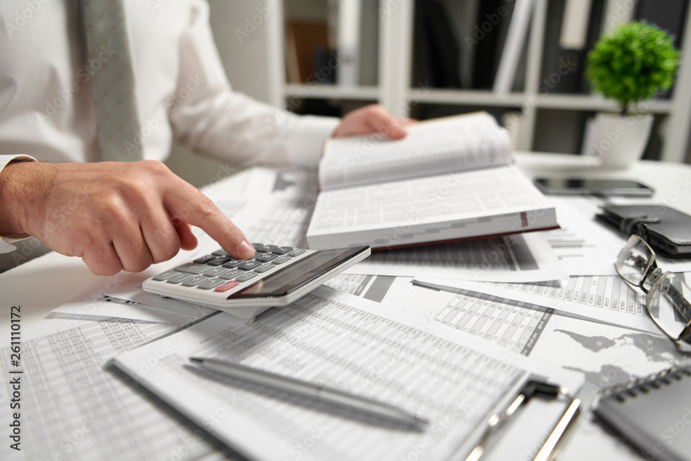 Businessman working at office and calculating finance, reads and writes reports. Business financial accounting concept. Businessman working at office and calculating finance, reads and writes reports. Business financial accounting concept.