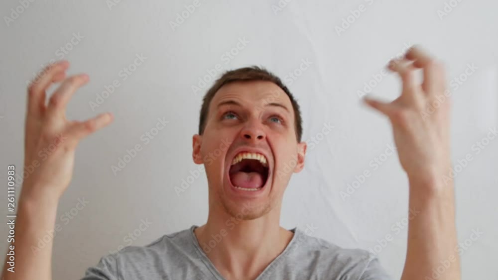 The man shows a quick change of mood on the camera on a white background. The concept of rapid mood swings from angry to peaceful.