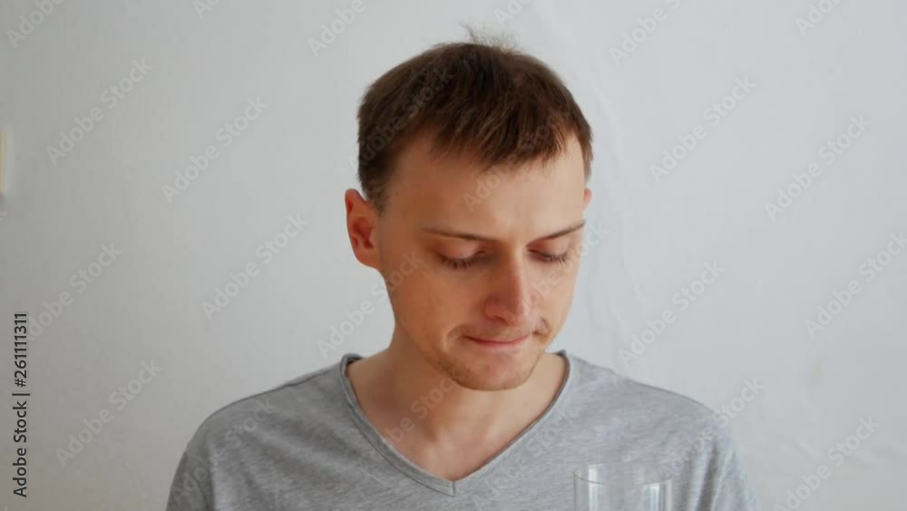 a young man drinks medicine with a glass of water a young man drinks medicine with a glass of water