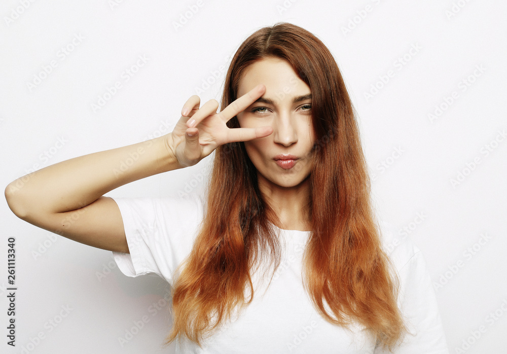 Portrait of gorgeous woman looking at camera with smile and showing peace sign with fingers Portrait of gorgeous woman looking at camera with smile and showing peace sign with fingers