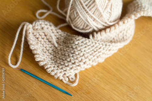 Extremely close-up knitting from beige yarn, needle, crochet hooks. Work on a new product. Selective soft focus.