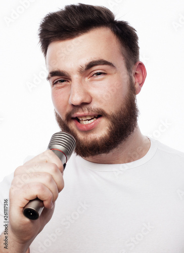 young bearded man in white shirt singing in microphone