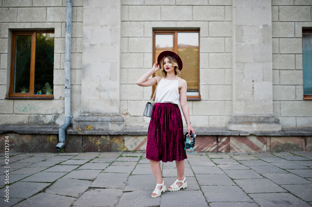 Fashionable and beautiful blonde model girl in stylish red velvet velour skirt, white blouse and hat, posed with phone and earphones. Fashionable and beautiful blonde model girl in stylish red velvet velour skirt, white blouse and hat, posed with phone and earphones.
