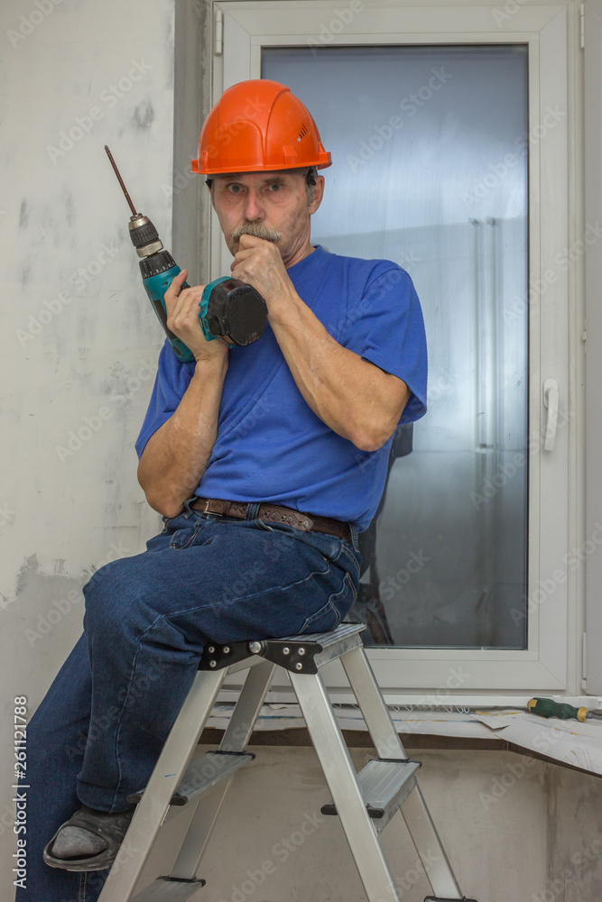 Elderly worker sits at a loss on a ladder, he makes repairs Elderly worker sits at a loss on a ladder, he makes repairs