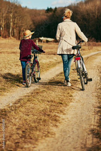 Mother and daughter with bicycles on countryside.