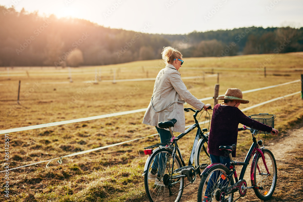 Fototapeta premium Mother and daughter with bicycles on countryside.