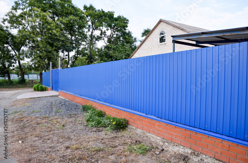 Fence and gate from sheets of blue corrugated metal.