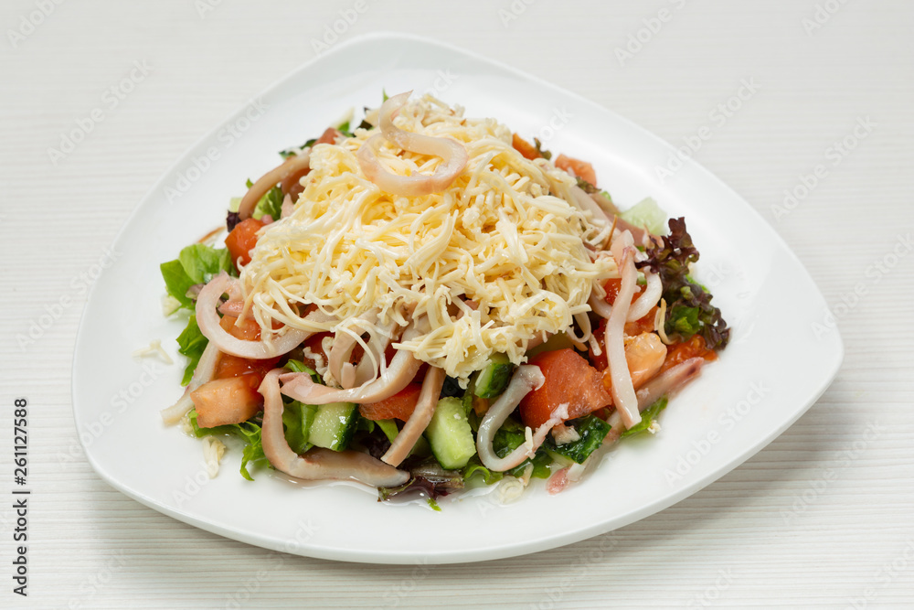 salad of fresh vegetables and greens, with squid rings and cheese, on a white plate salad of fresh vegetables and greens, with squid rings and cheese, on a white plate