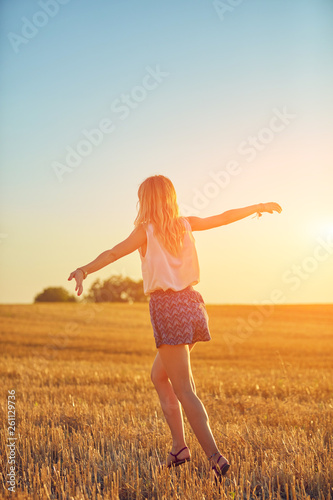 Cute young woman jumping in a wheat field. © astrosystem