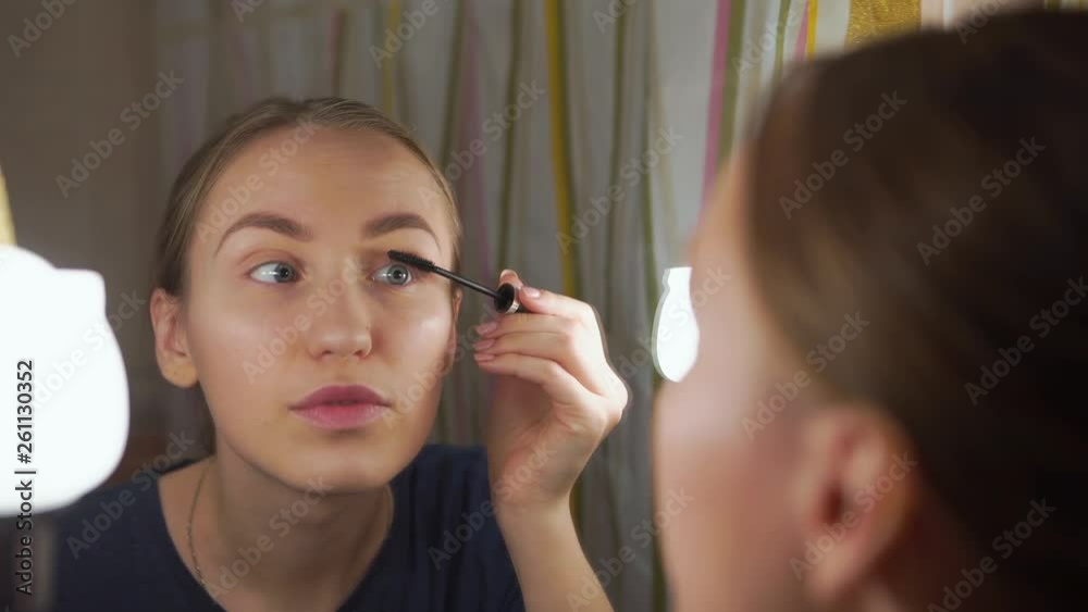 pretty young girl does a natural makeup, paints eyebrows, eyelashes in front of mirror pretty young girl does a natural makeup, paints eyebrows, eyelashes in front of mirror