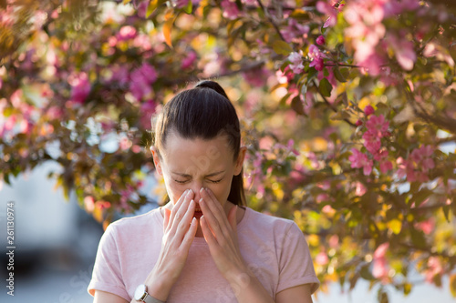 Woman sneezing because of spring pollen allergy photo