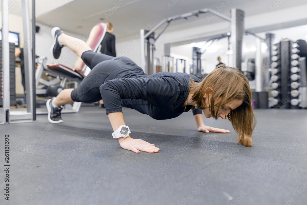 Φωτογραφία Young fitness woman working out doing push-ups on floor in sport gym