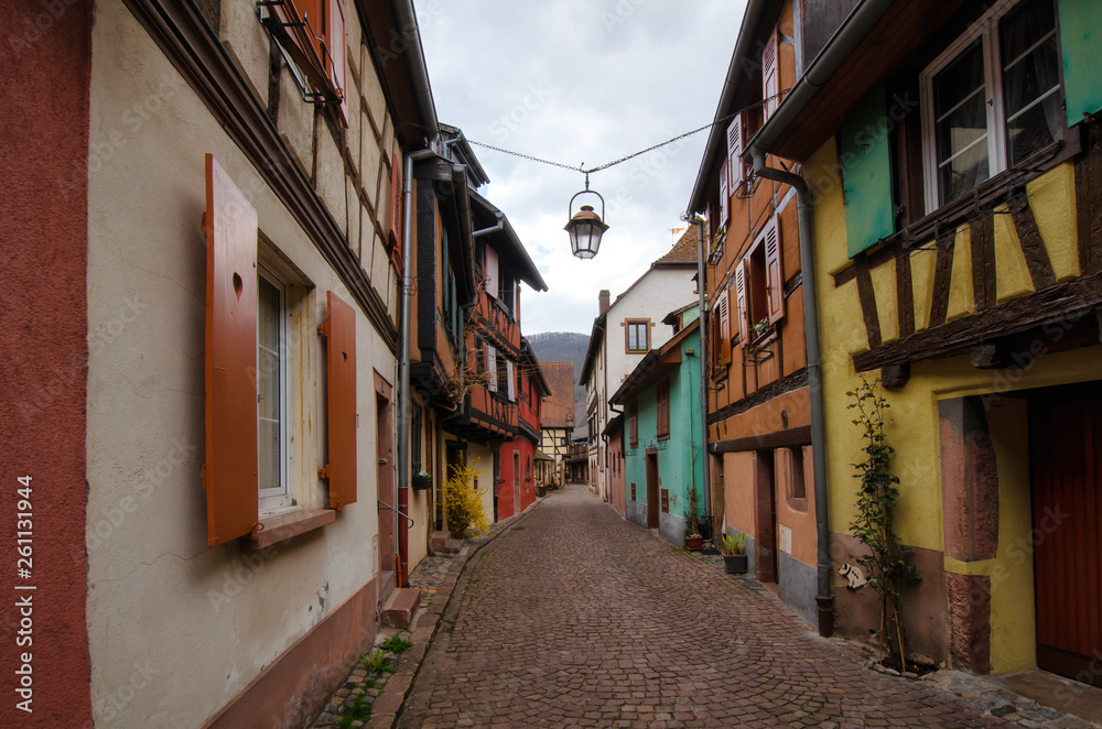 A view along the street with old multi-colored half-timbered houses. Alsace. France. Town Kaysersberg. A lantern hangs above the street.