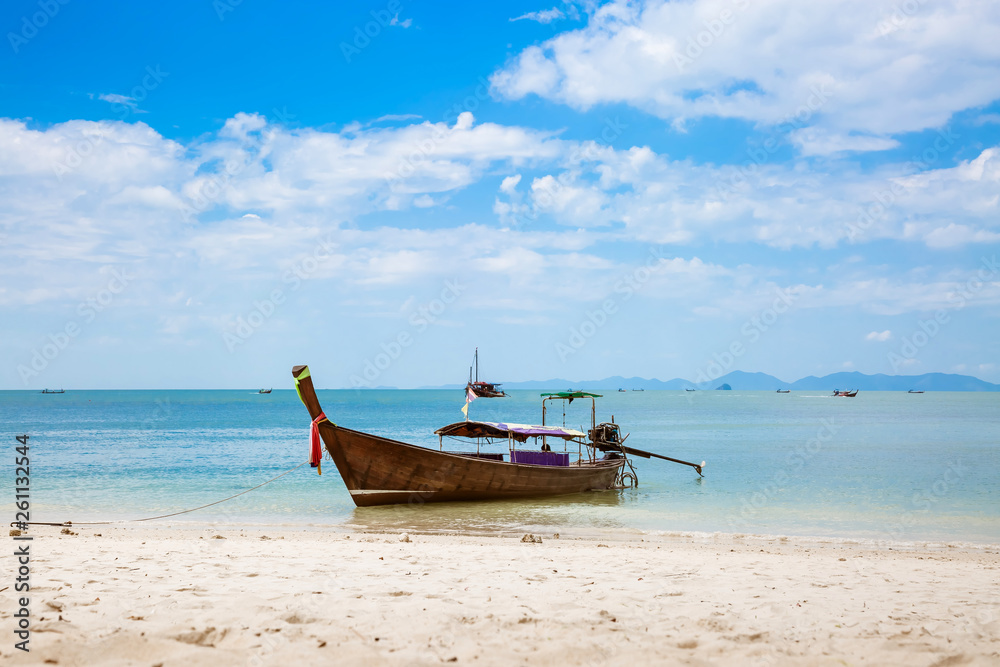 Asian taxi. Long-tailed boat on a tropical white sand beach. Blue sky and sea, mountains on the horizon. It is cloudy.
