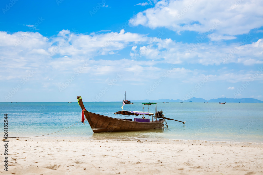 Asian taxi. Long-tailed boat on a tropical white sand beach. Blue sky and sea, mountains on the horizon. It is cloudy. Asian taxi. Long-tailed boat on a tropical white sand beach. Blue sky and sea, mountains on the horizon. It is cloudy.