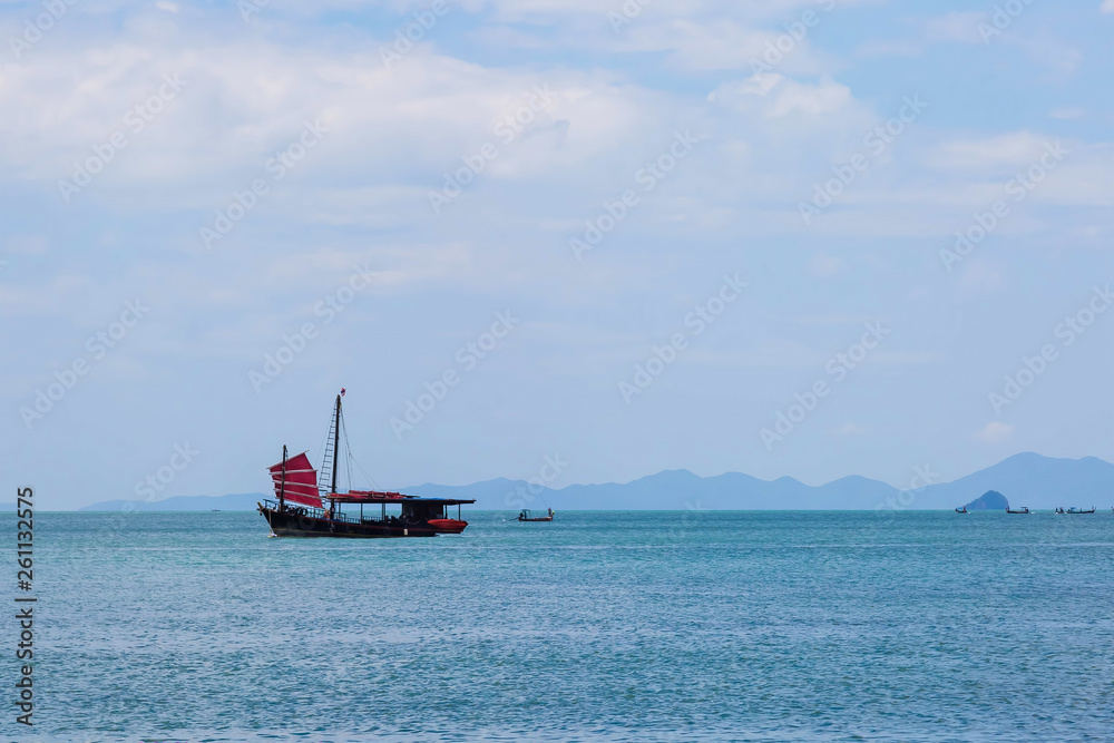 Black sailing ship with red sails sailing on the blue sea.