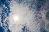 Texture. Bottom up view. The sun behind the clouds. Deep blue sky.