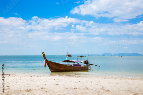 Asian taxi. Long-tailed boat on a tropical white sand beach. Blue sky and sea  mountains on the horizon. It is cloudy.