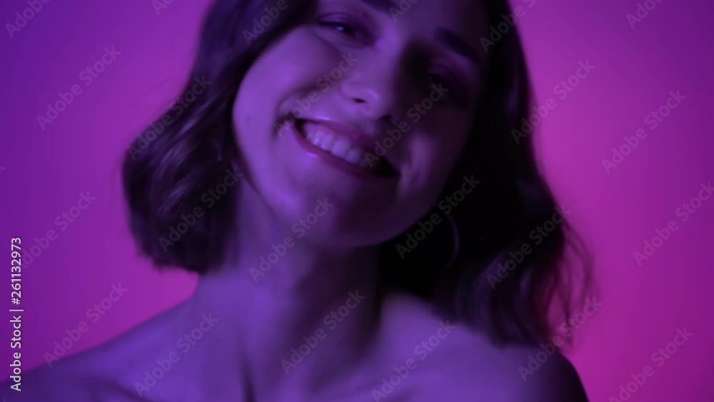 Closeup shoot of young pretty girl laughing happily in front of the camera with neon blue background Closeup shoot of young pretty girl laughing happily in front of the camera with neon blue background