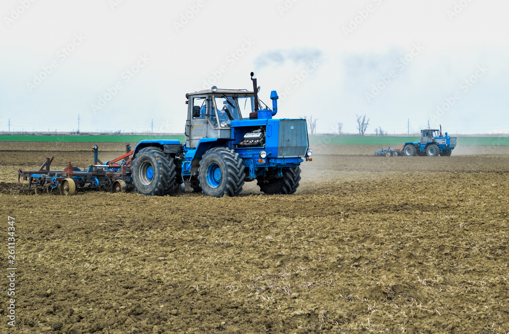 Lush and loosen the soil on the field before sowing. The tractor plows a field with a plow Lush and loosen the soil on the field before sowing. The tractor plows a field with a plow