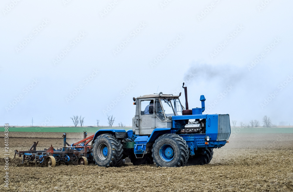 Lush and loosen the soil on the field before sowing. The tractor plows a field with a plow Lush and loosen the soil on the field before sowing. The tractor plows a field with a plow