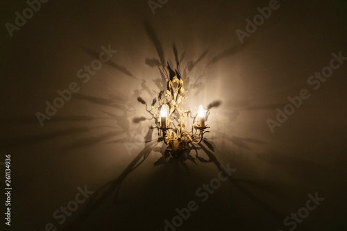 antique chandelier with warm light casting numerous shadows on the wall