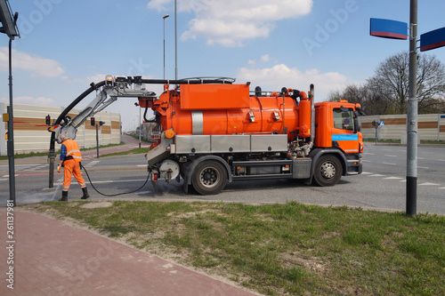 Cleaning sewer manholes. Worker and specialist car.