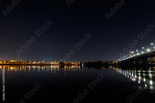 dark cityscape with buildings, bridge, lights, river and night sky