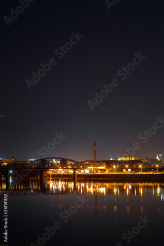 dark cityscape with buildings, lights, river and night sky